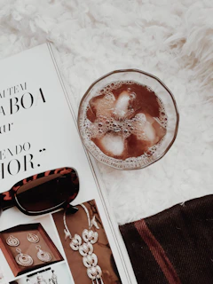 A curated flat lay of vintage sunglasses, a sunhat, and glossy fashion magazines on a wooden table