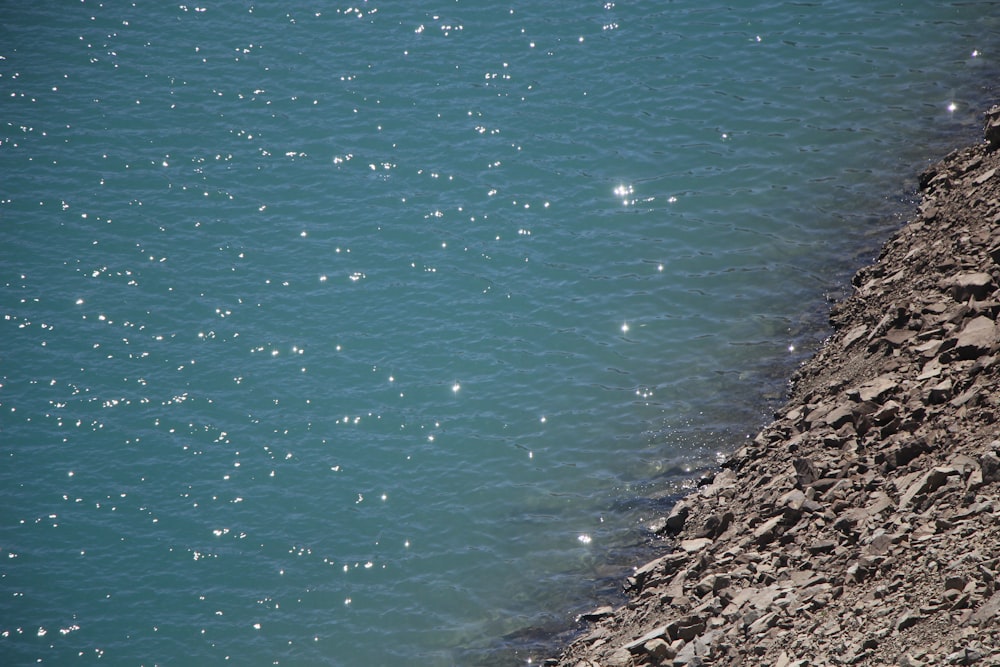 a rocky beach with a body of water in the background