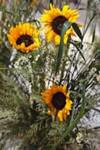 A vibrant birthday centerpiece featuring sunflowers and bright daisies in a rustic vase.