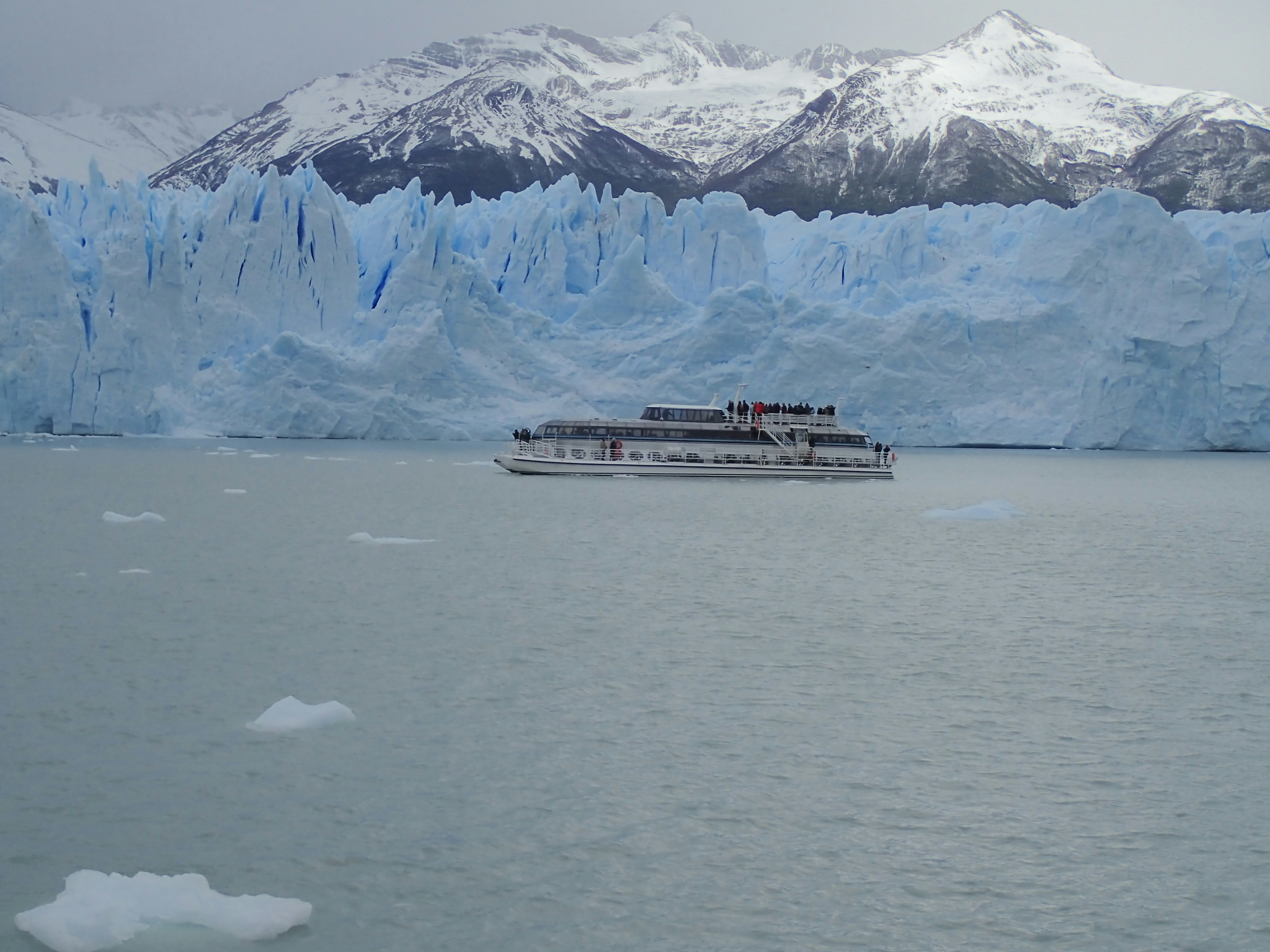 a boat in the water with snowy mountains in the background