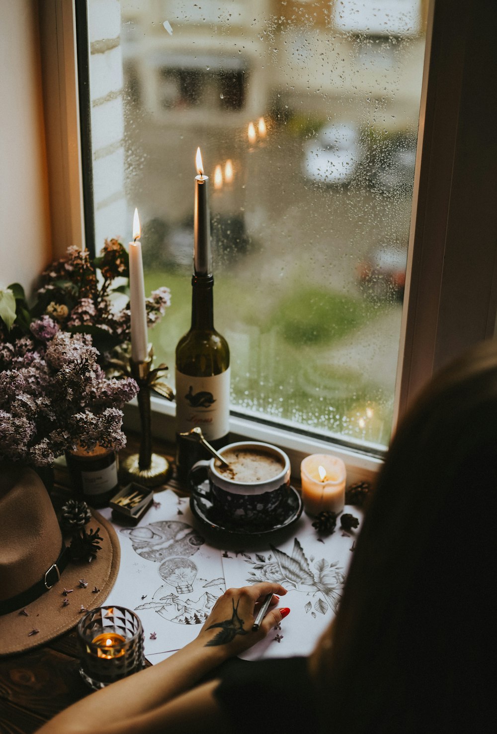 a person sitting at a table with a wine bottle and candles