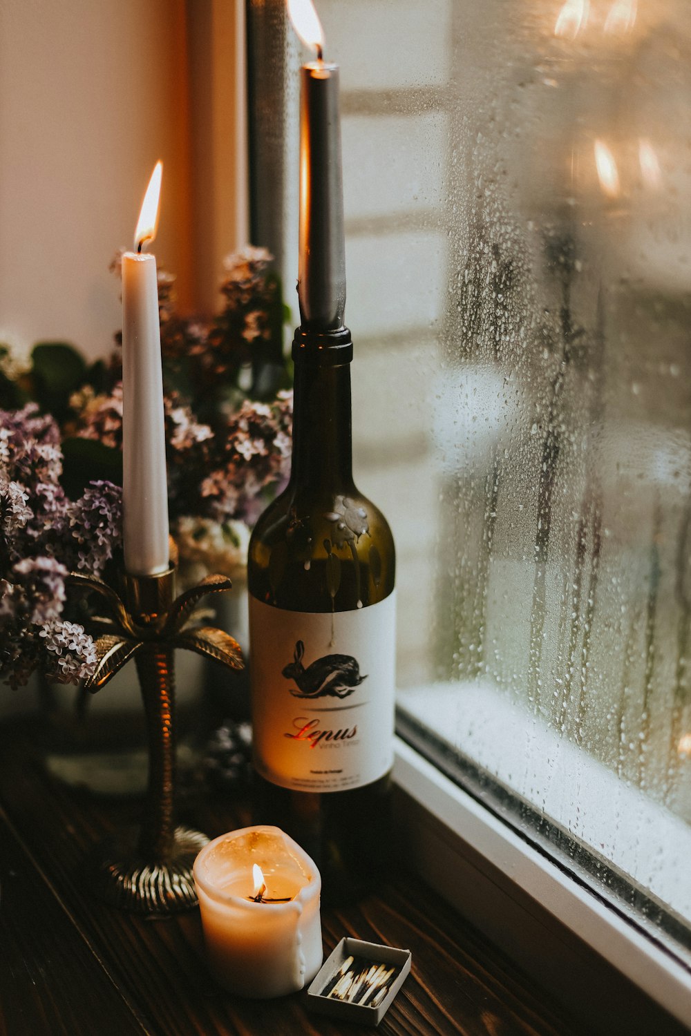 a bottle of wine next to a candle and a glass of wine