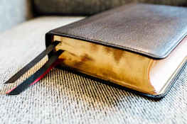 Close-up of hands holding a deep crimson book titled 'Arcanum Imperium'.