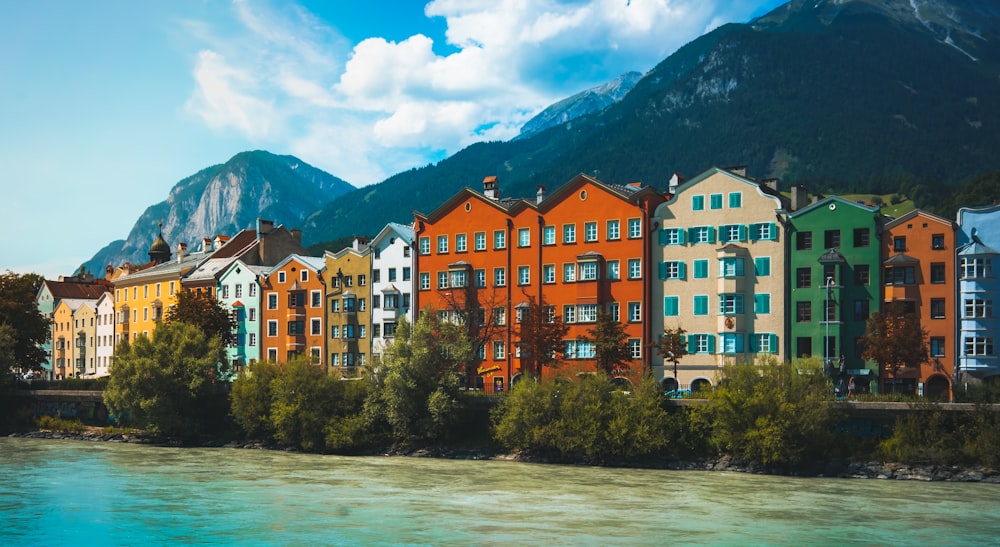 a body of water with buildings along it and mountains in the background