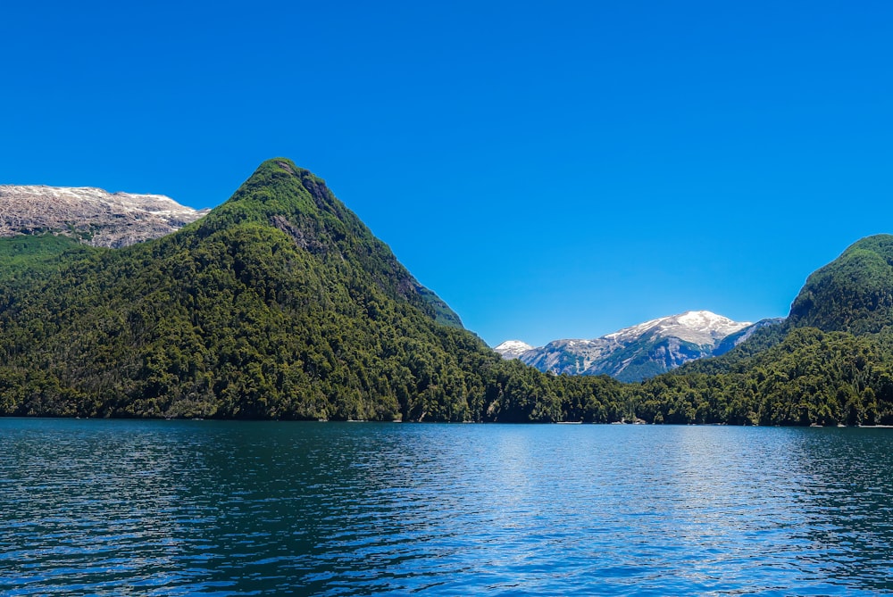 a body of water with trees and mountains in the background