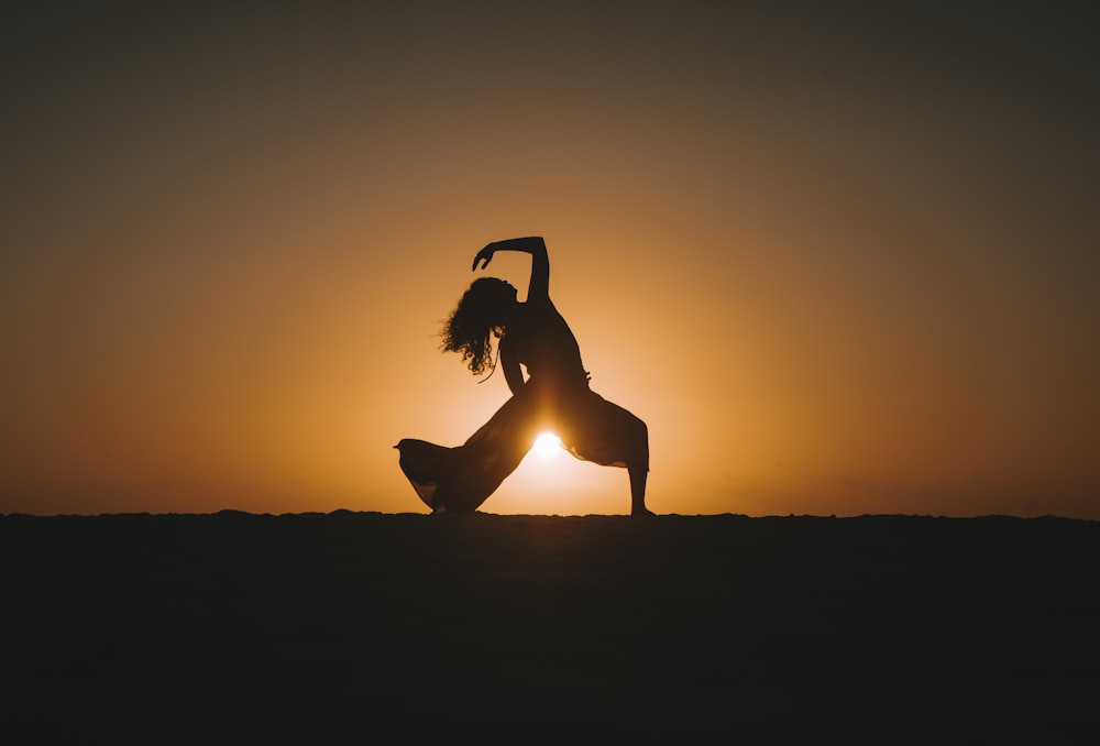 a person doing a handstand in front of a sunset