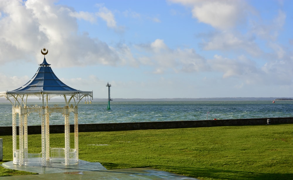 a gazebo on a grassy hill by the water