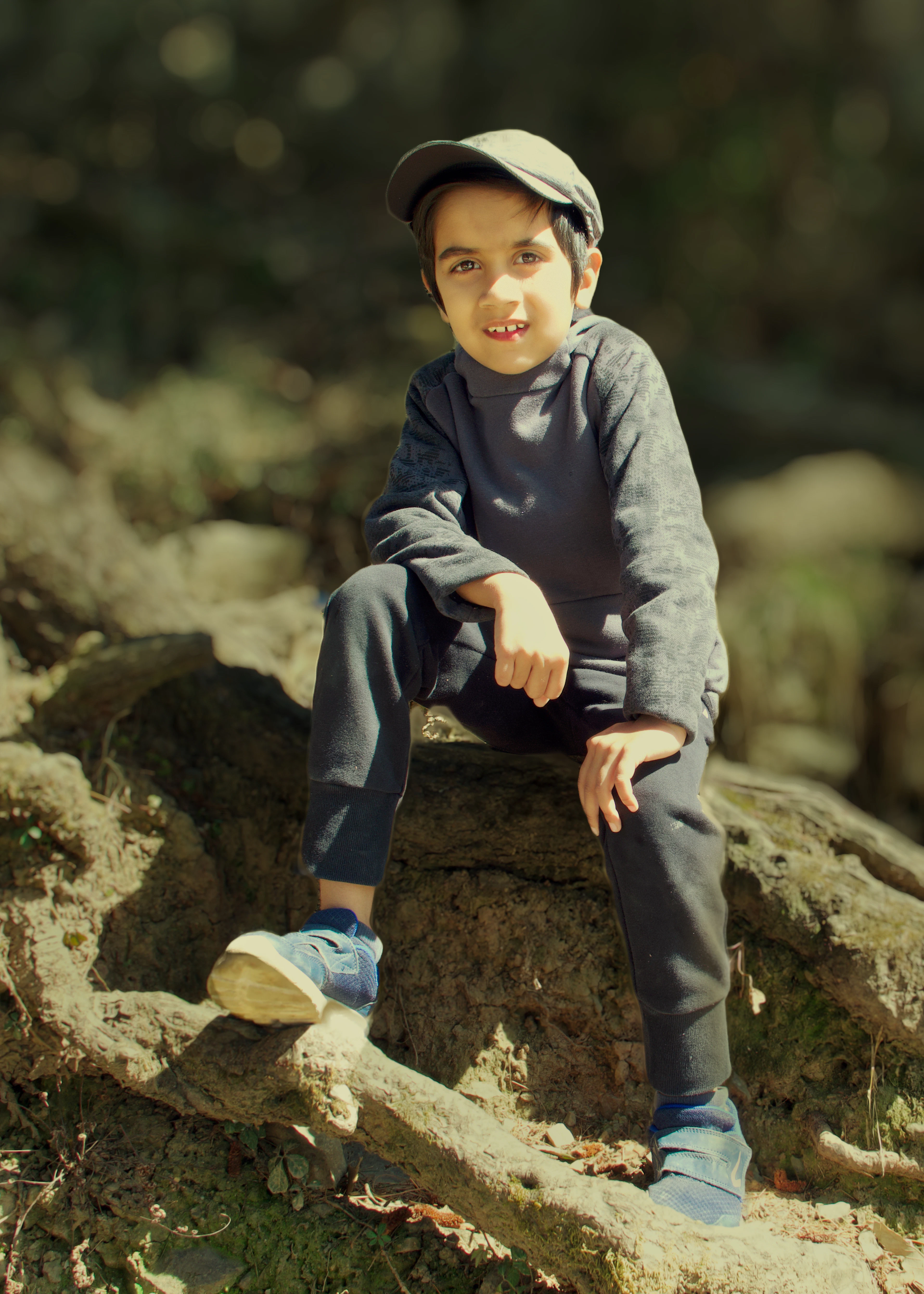 A boy in trail pants sitting on a mossy log