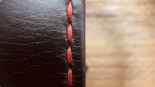 Close-up shot of premium black leather texture with fine stitching details.