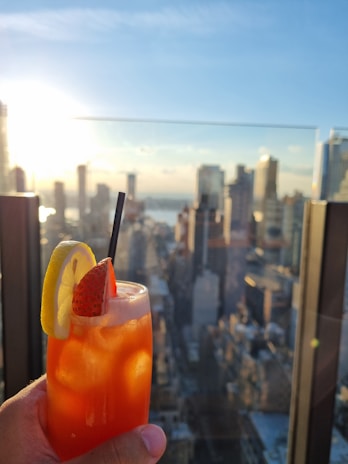 Brightly colored cocktail with a citrus garnish, sparkling under warm ambient lighting.
