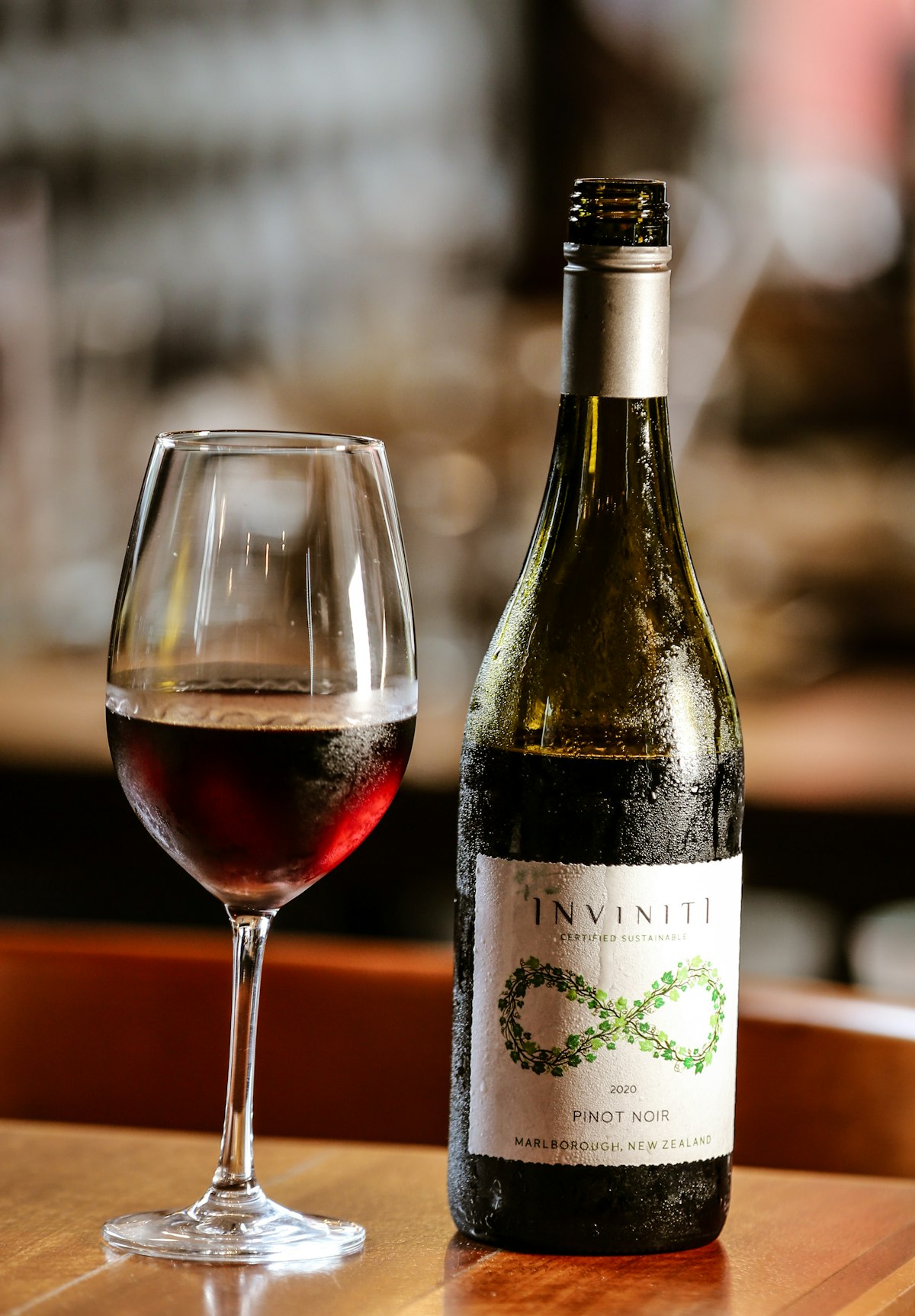 A bottle and glass of red wine on a rustic wood table
