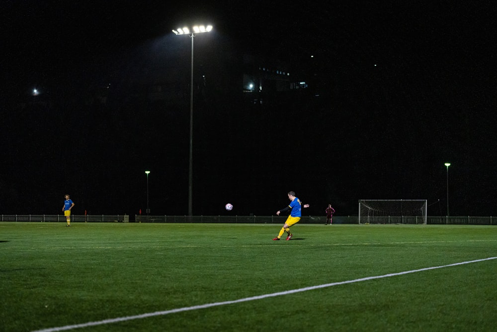 Una persona con una camisa azul jugando al fútbol por la noche