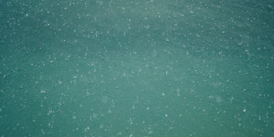 Close-up of water droplets on a transparent surface with soft turquoise hues.