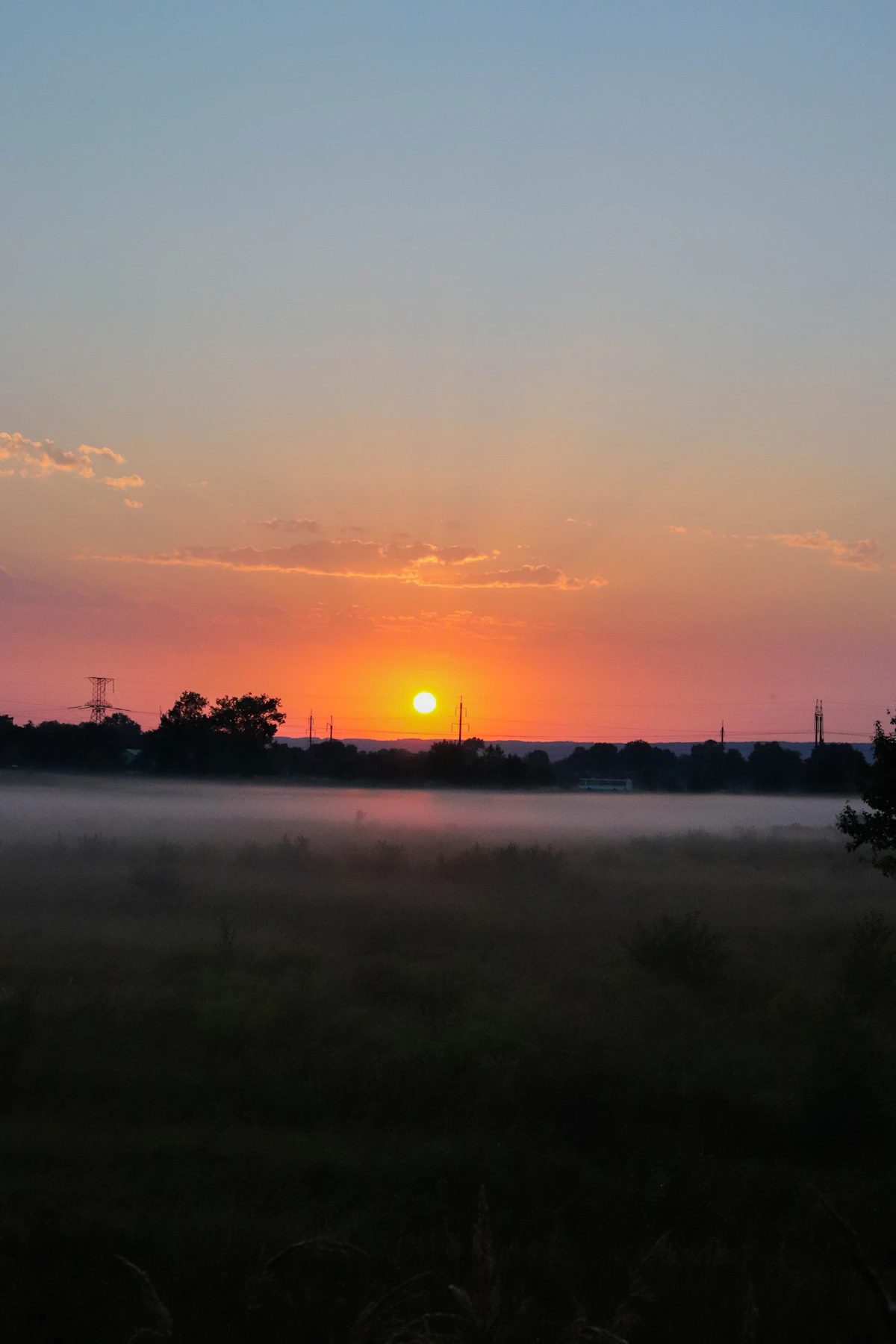 The sun rising over a calm, misty field