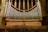 A large pipe organ is situated inside a cathedral, featuring numerous silver pipes arranged symmetrically against a backdrop of stained glass windows and ornate stone columns. The seating area in front of the organ is made up of wooden chairs.