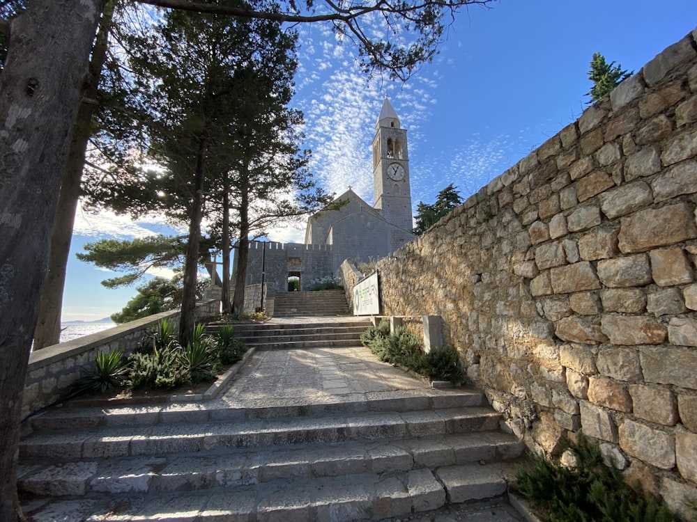 a stone staircase leading up to a stone building with a clock tower