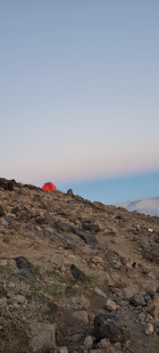 Traditional Bedouin tents nestled at the base of rocky hills under a vast blue sky.