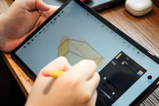 a person holding a pencil and a tablet