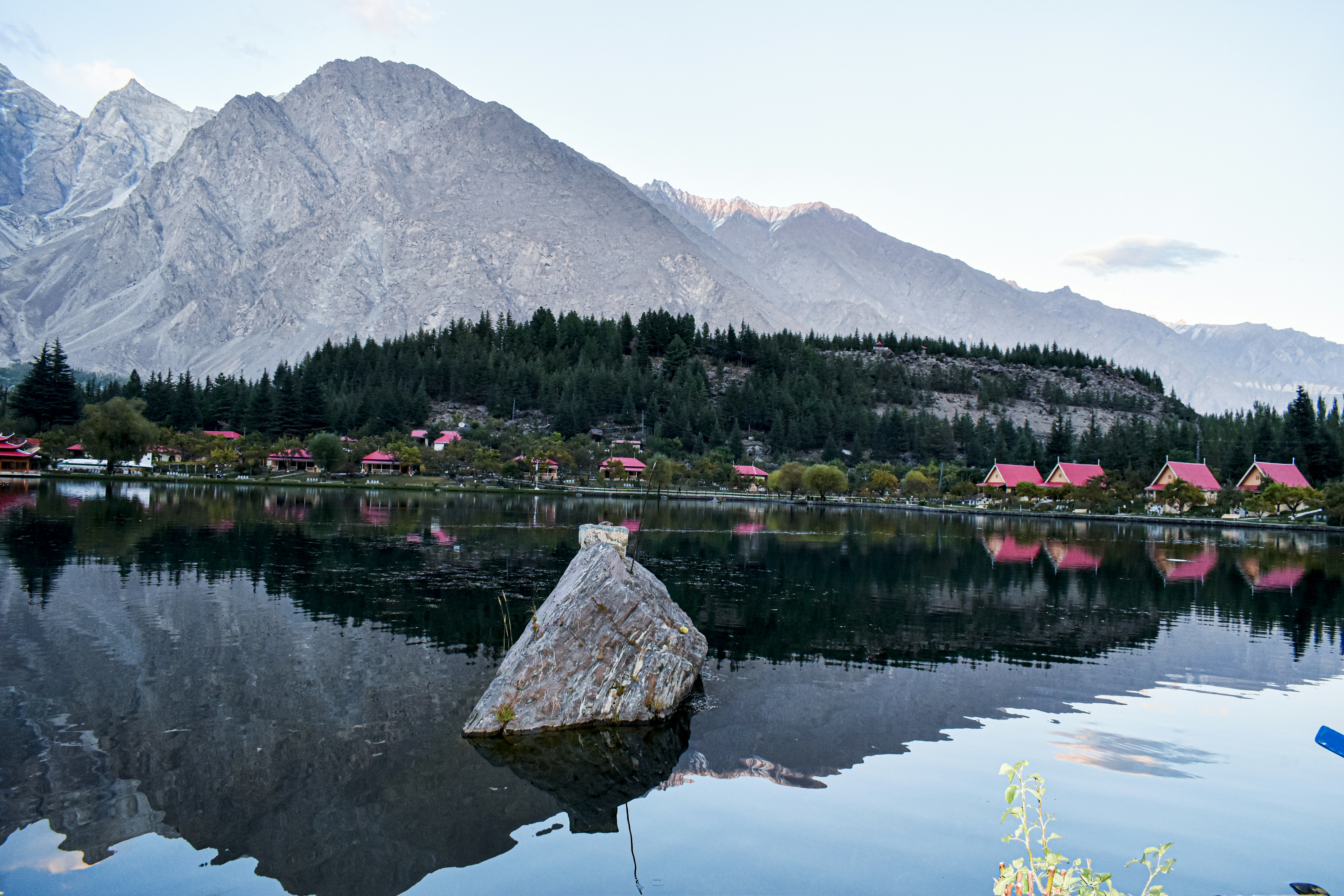 a body of water with a rock in it and a mountain in the background