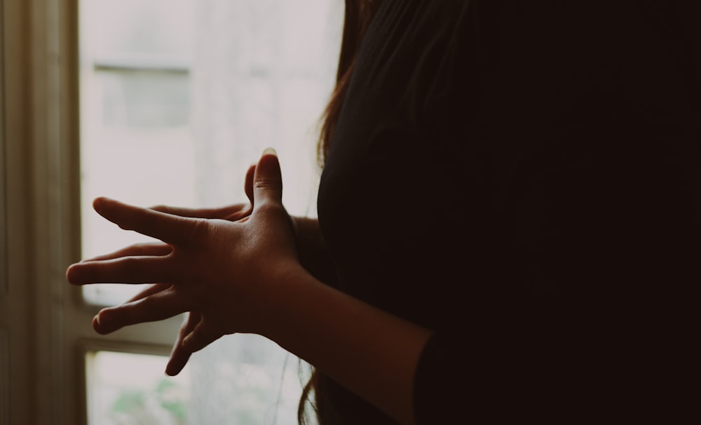 a woman's hand pointing at a window