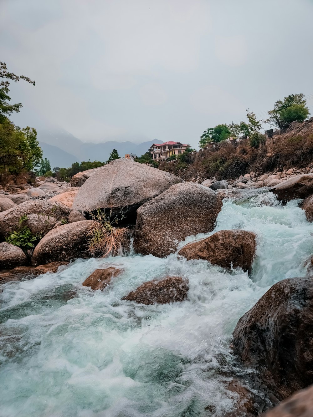 a river with rocks and a house in the background