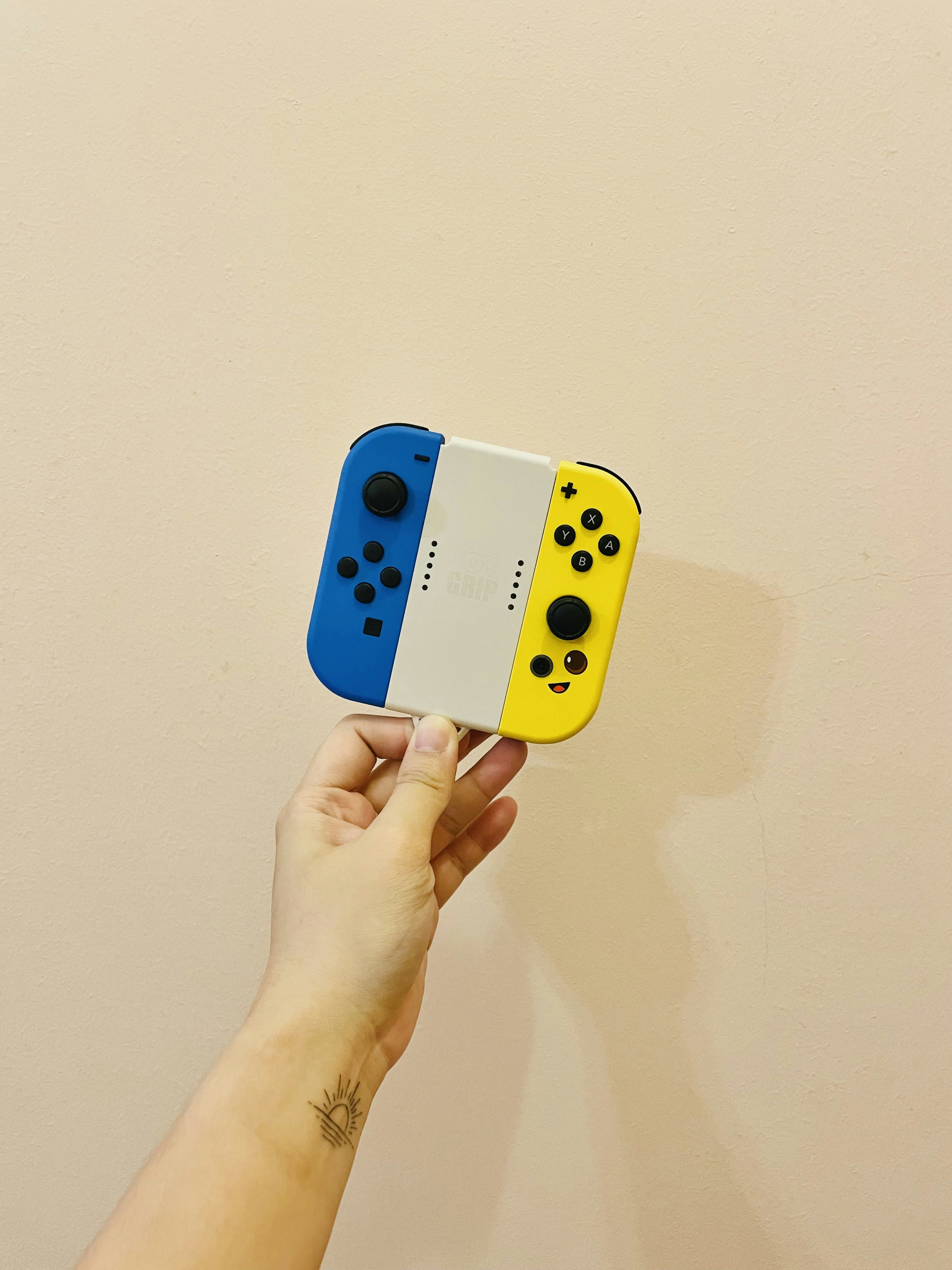 una mano che tiene un controller di gioco giallo e nero