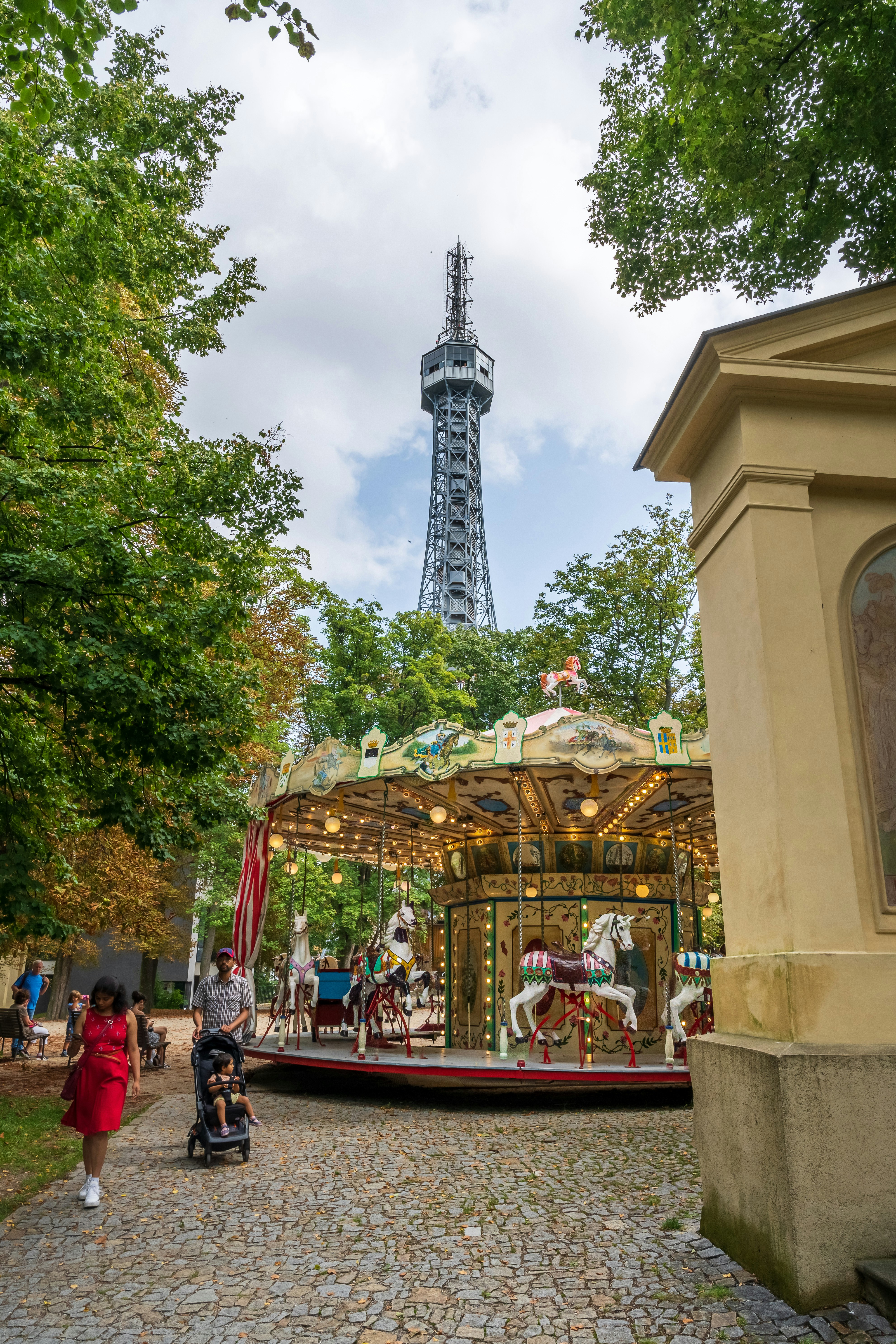a group of people walking around a park with a tower in the background