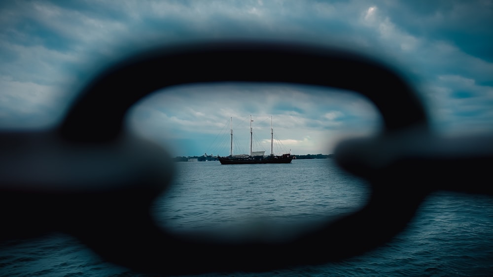 a view through a hole in a boat window of a sailboat on the water