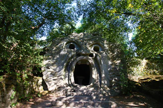a stone structure with a hole in it surrounded by trees