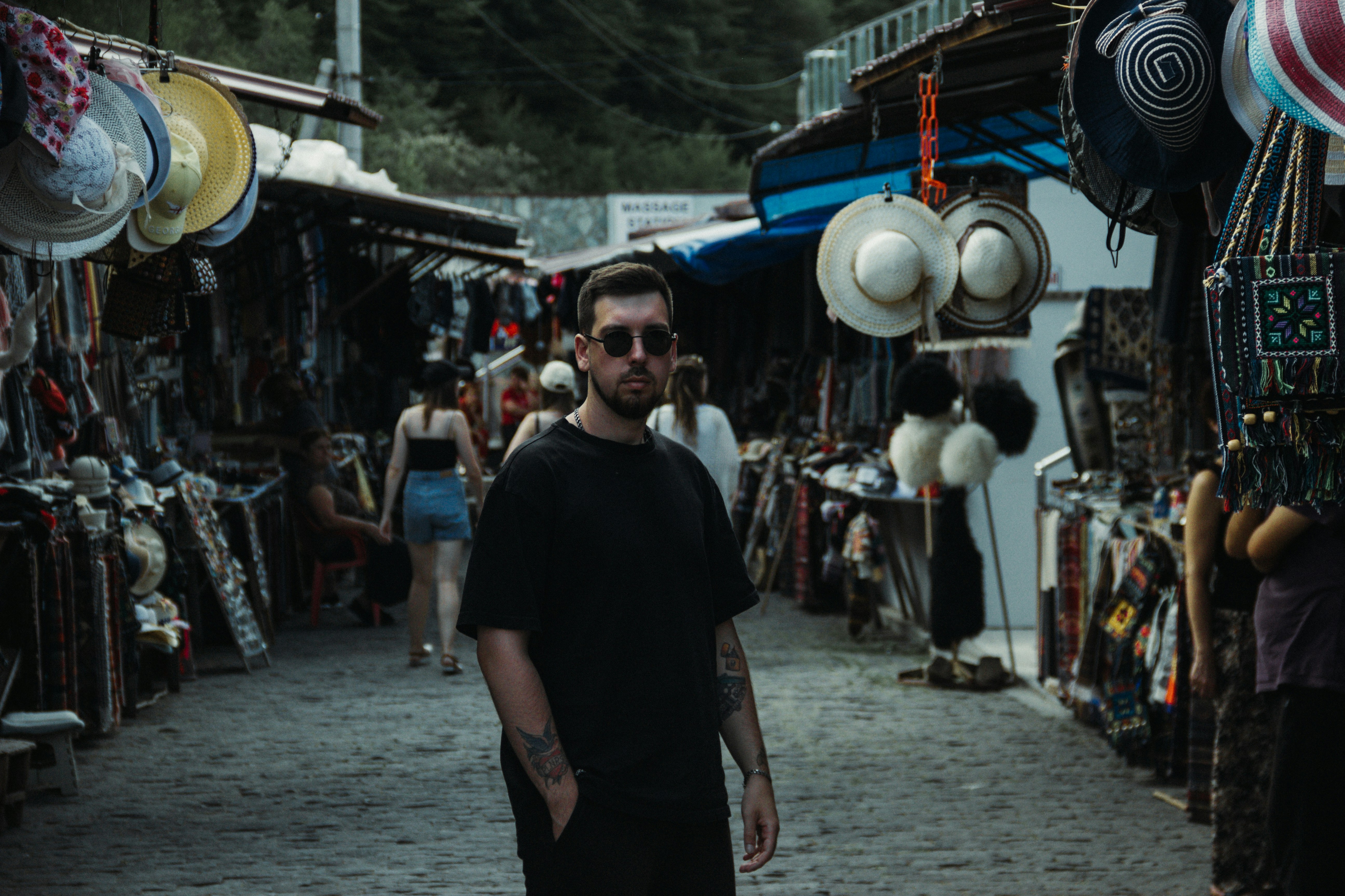 a man standing in front of a street with many hats on it, 