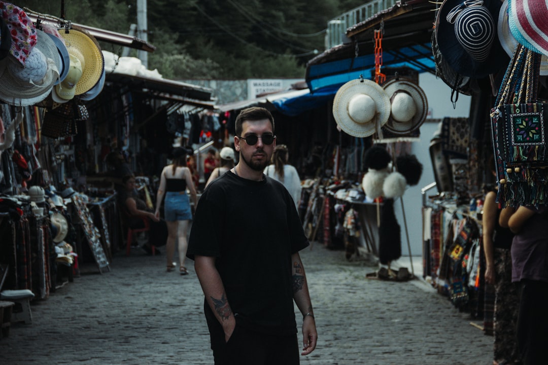 a man standing in front of a street with many hats on it,
