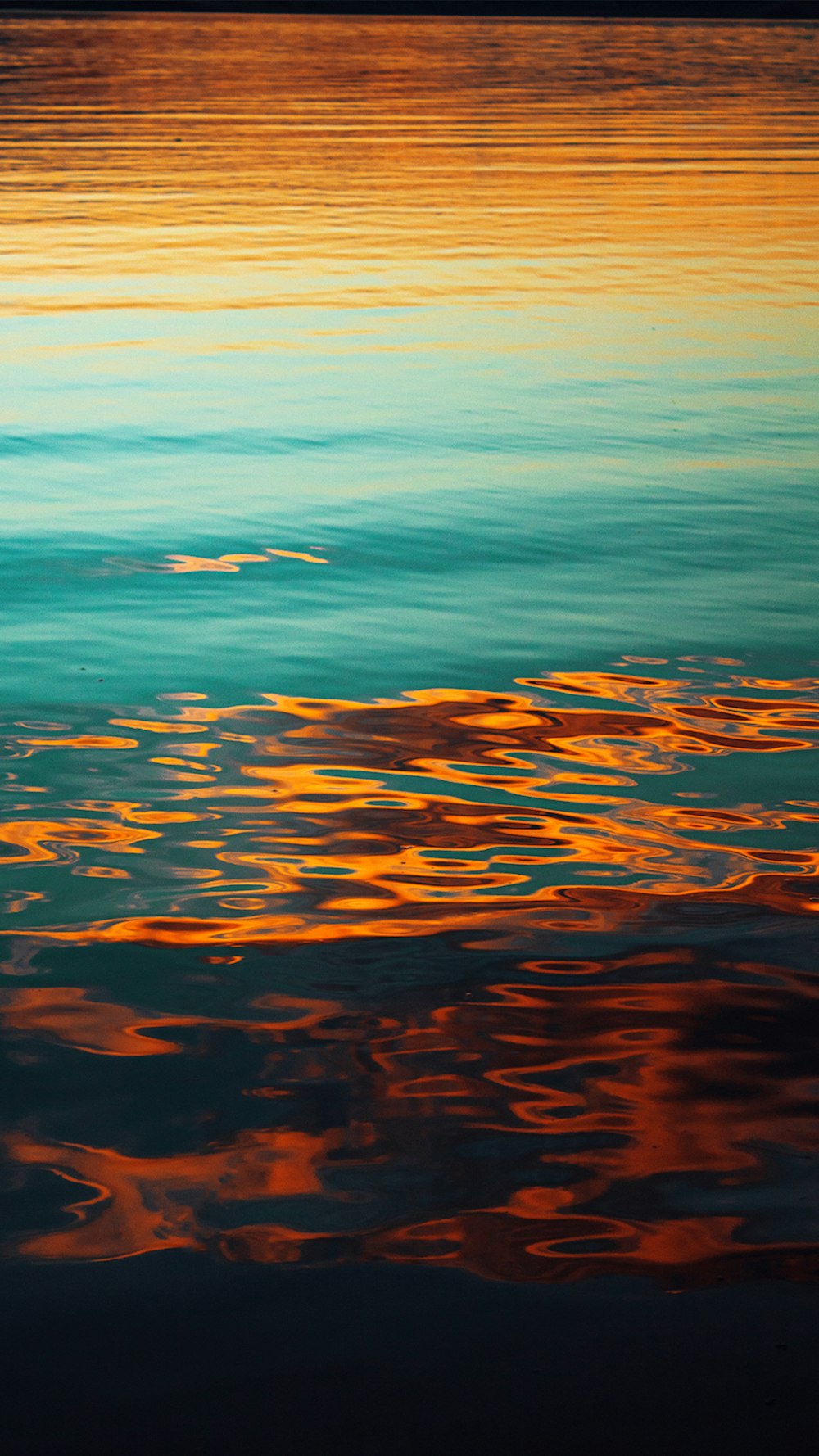 a body of water with orange and blue sky