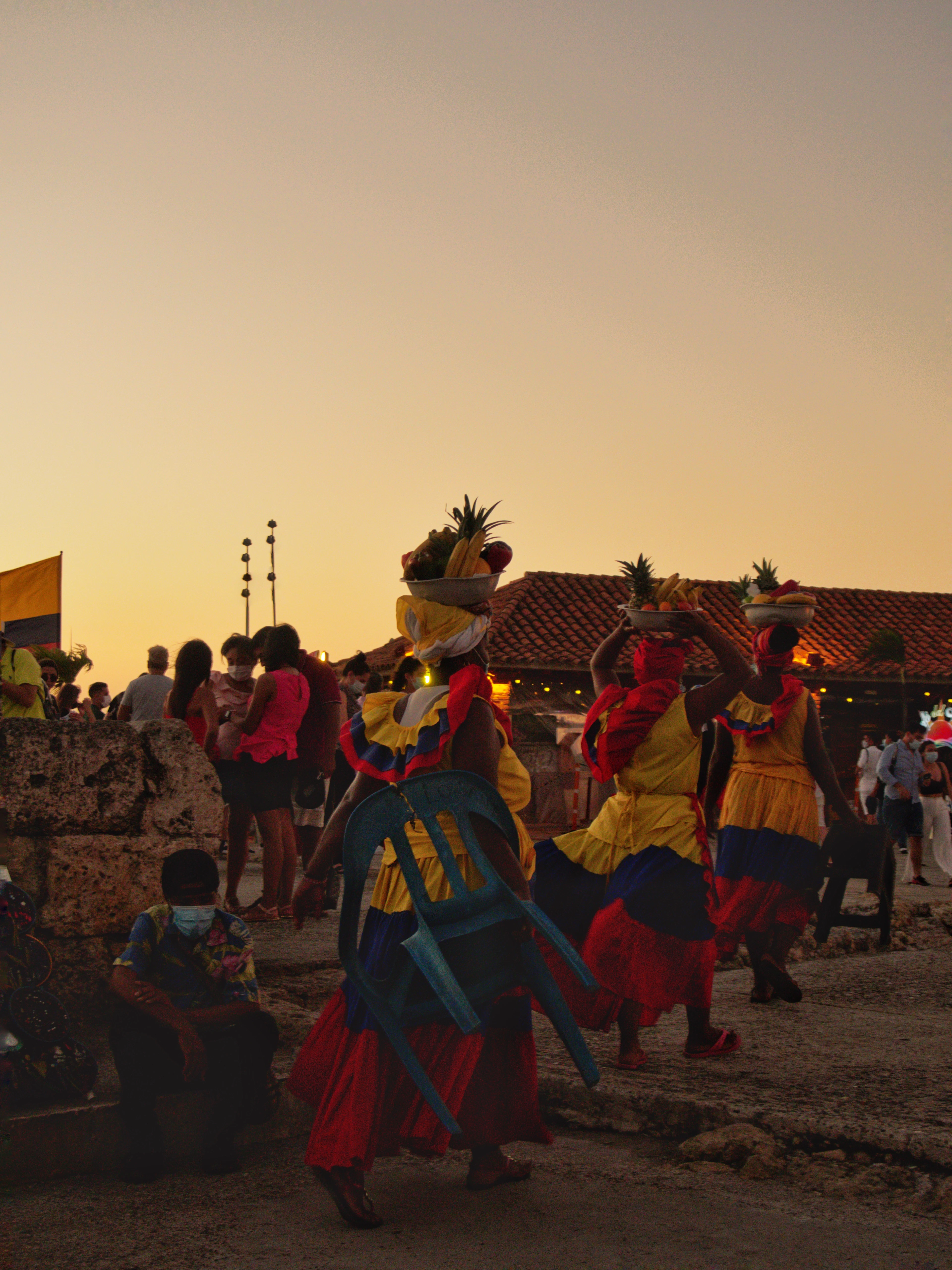 Palenqueras dance atop Cartagena's fortress walls as the sky turns orange at sunset.