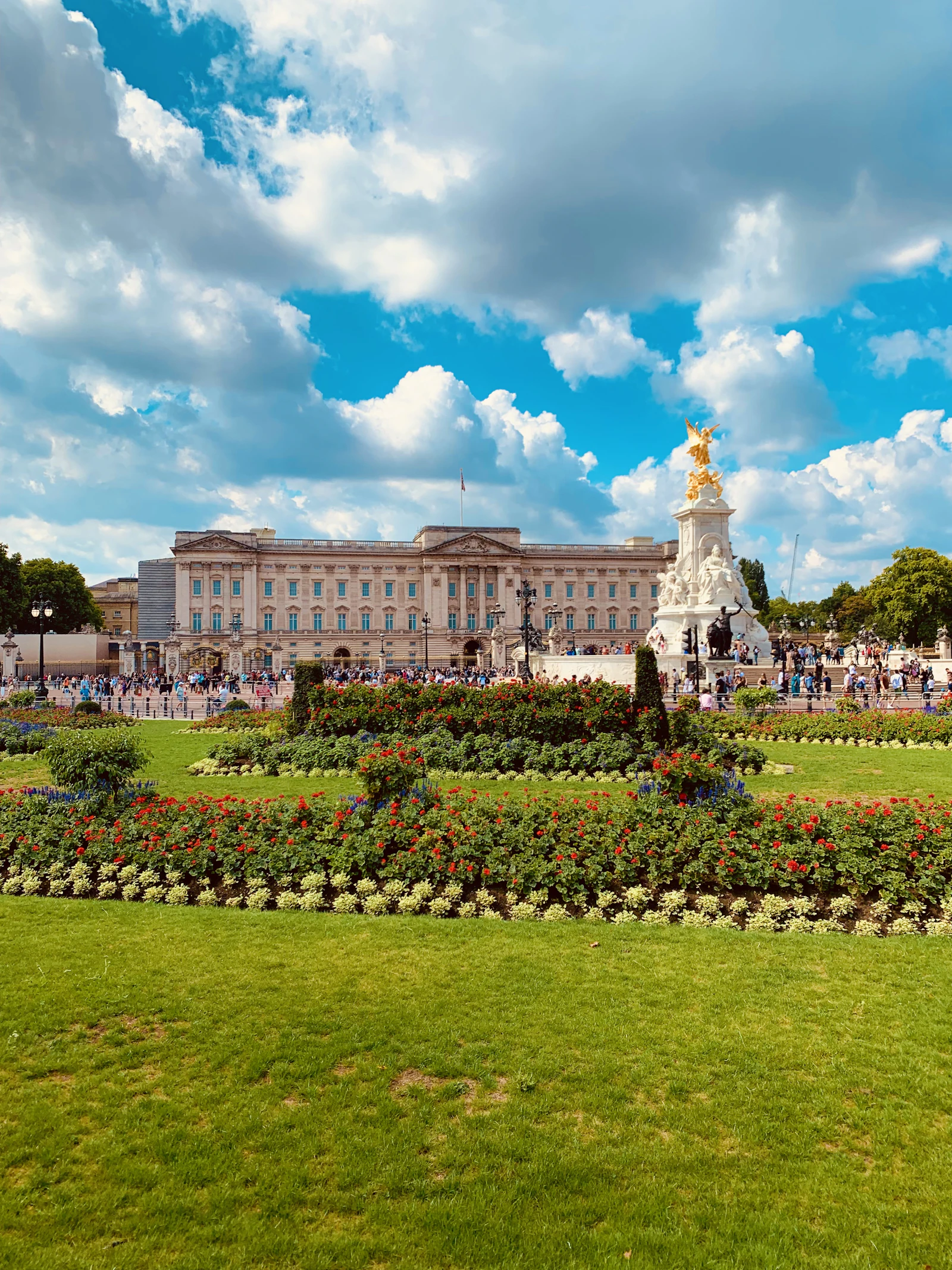 Travel photograph: Buckingham Palace and the Victoria Memorial beyond bright summer flower beds.