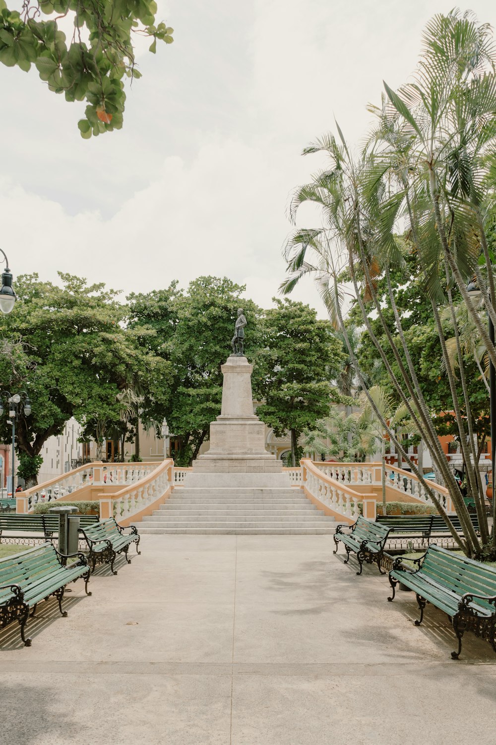 a stone pathway with benches and trees