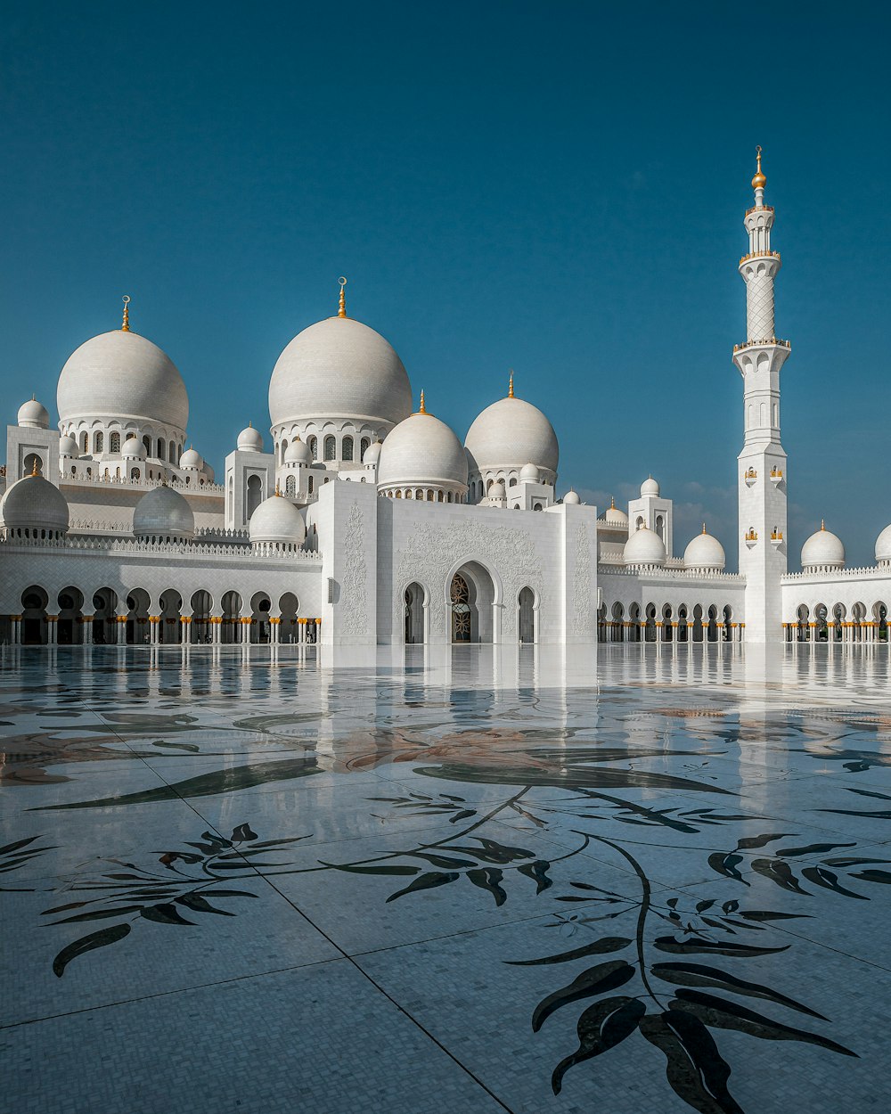 a large white building with domed roofs with Sheikh Zayed Mosque in the background