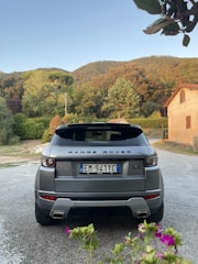 A vibrant animated garden with detailed flowers and leaves surrounding a sleek Land Rover off-road vehicle in the top left corner.