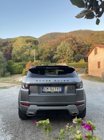 A beautifully restored Land Rover parked outdoors with lush greenery in the background.