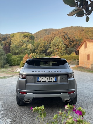 A vibrant animated garden with detailed flowers and leaves surrounding a sleek Land Rover off-road vehicle in the top left corner.