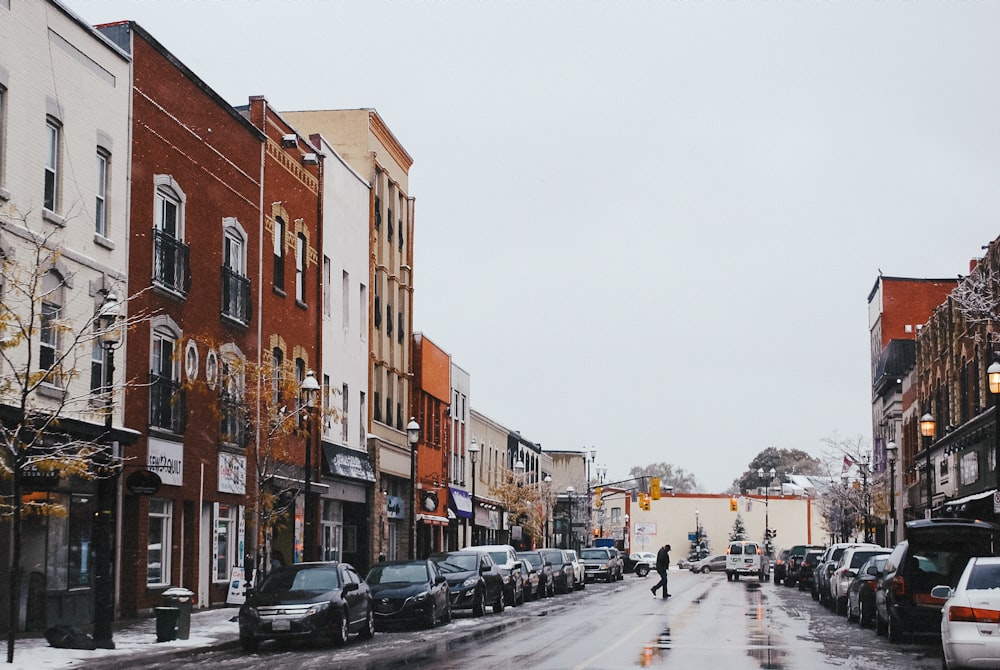 a snowy street with cars parked on the side