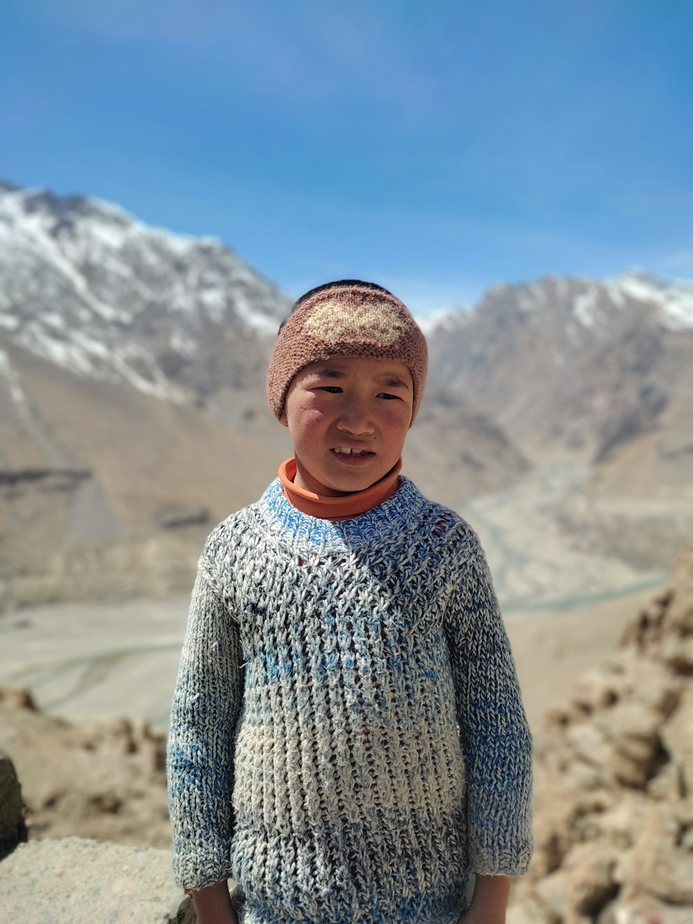 a boy standing on a rocky hillside