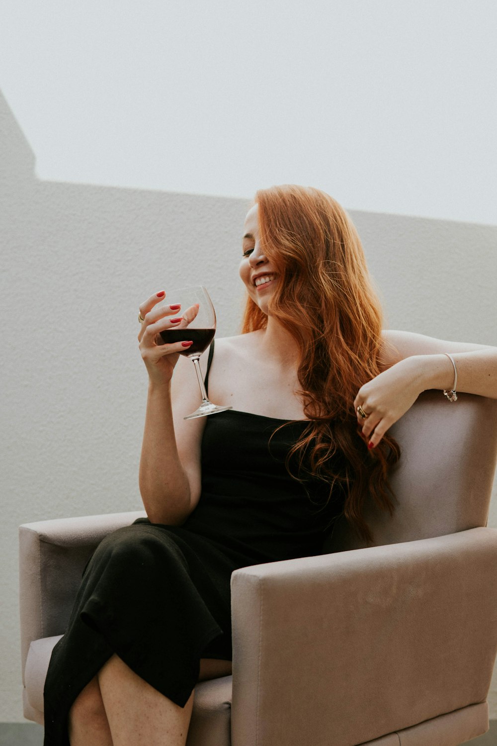 a woman sitting on a couch and holding a glass of wine