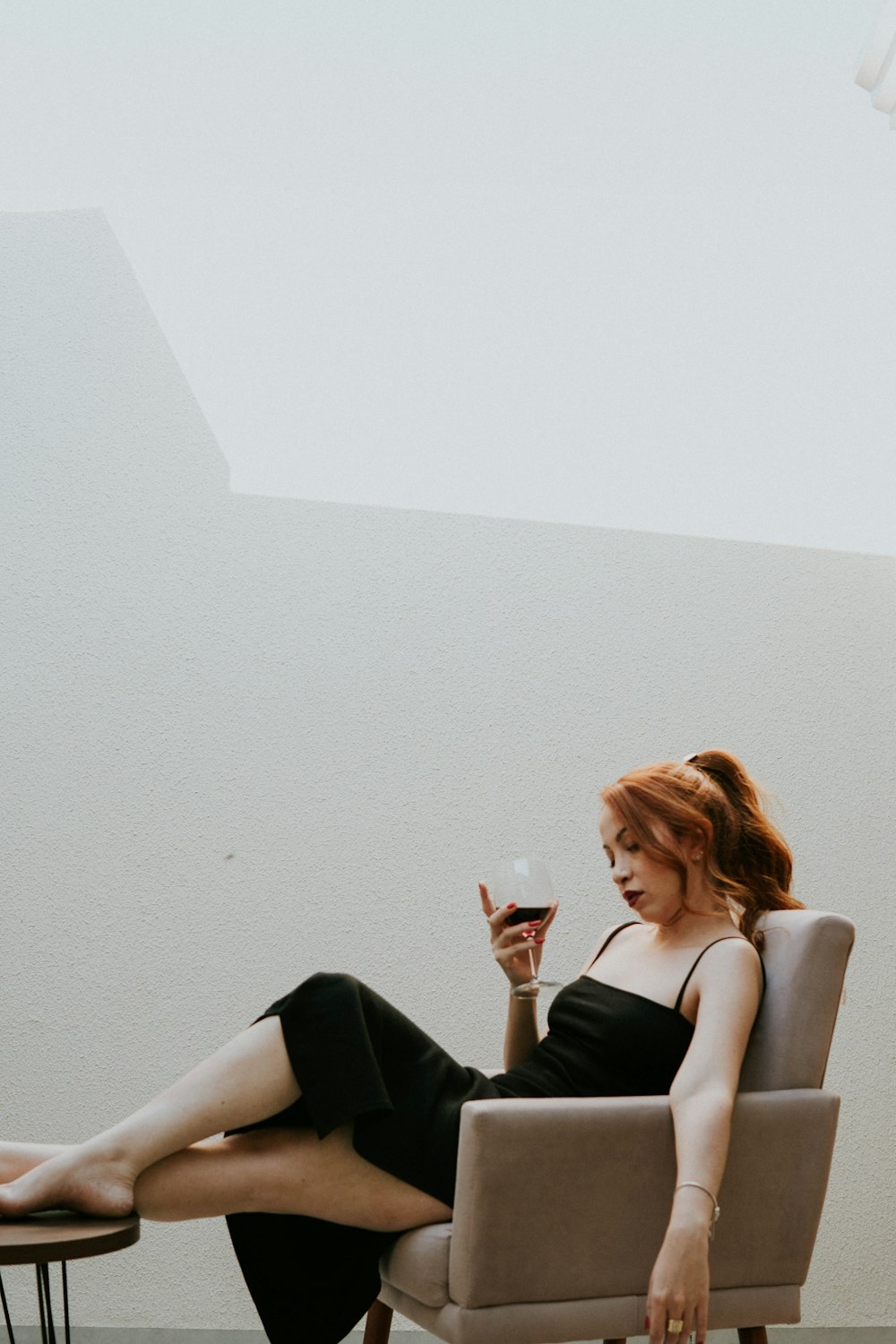 a woman sitting on a couch drinking from a glass