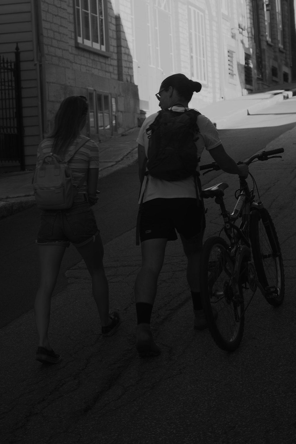 a man and woman walking down a sidewalk next to a bicycle