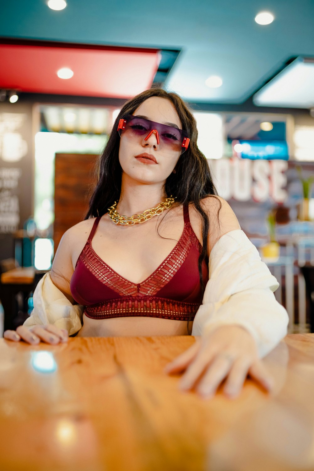 a woman wearing a red and white dress and sunglasses sitting at a table