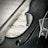 A close-up view of a violin intersecting with a sheet of music. The strings and body of the violin contrast with the musical notes printed on the page. The scene is captured in black and white, highlighting the textures and details of the wood grain and inked sheet.
