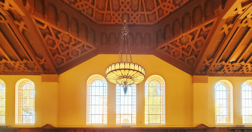 a chandelier from a ceiling in a room with windows