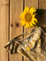 Handmade upcycled denim bag resting on a rustic wooden table with wildflowers.