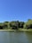A peaceful natural pond reflecting the sky, bordered by wildflowers and trees.