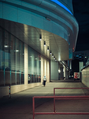 Guard patrol walking along a commercial building exterior at dusk.